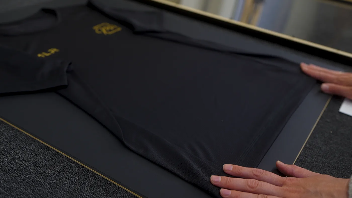 Des mains lissent le maillot sans plis sur le dos du cadre