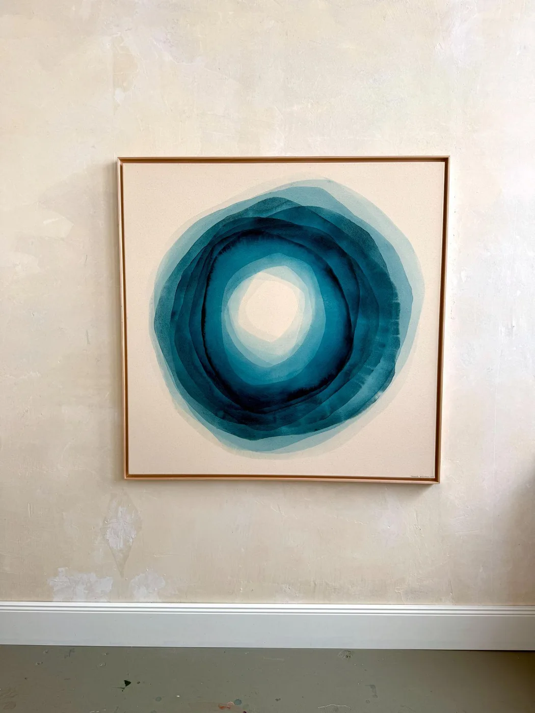 Œuvre circulaire de Johanne Bossmann aux tons pétrole et turquoise, dans un cadre en bois clair