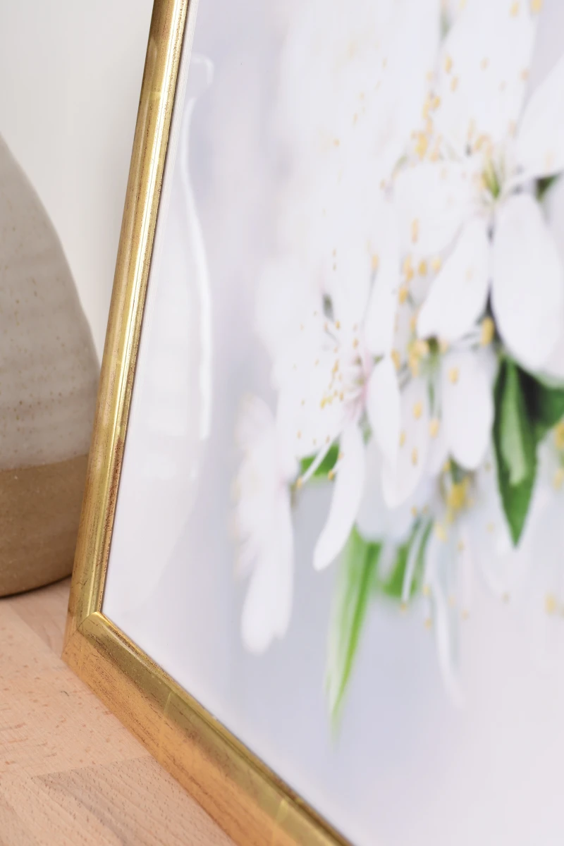 Découvre le cadre photo en bois Greta doré dans un intérieur chaleureux. Ce gros plan te permet d'admirer la finition MonCadrePréféré.