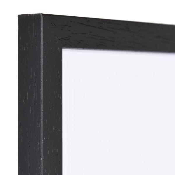 Vue de l'angle d'un cadre Ida en bois noir, avec sa texture visible et son profil étroit. MonCadrePréféré, la référence qualité.
