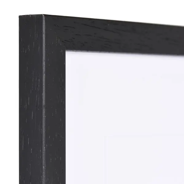 Vue de l'angle d'un cadre Ida en bois noir, avec sa texture visible et son profil étroit. MonCadrePréféré, la référence qualité.